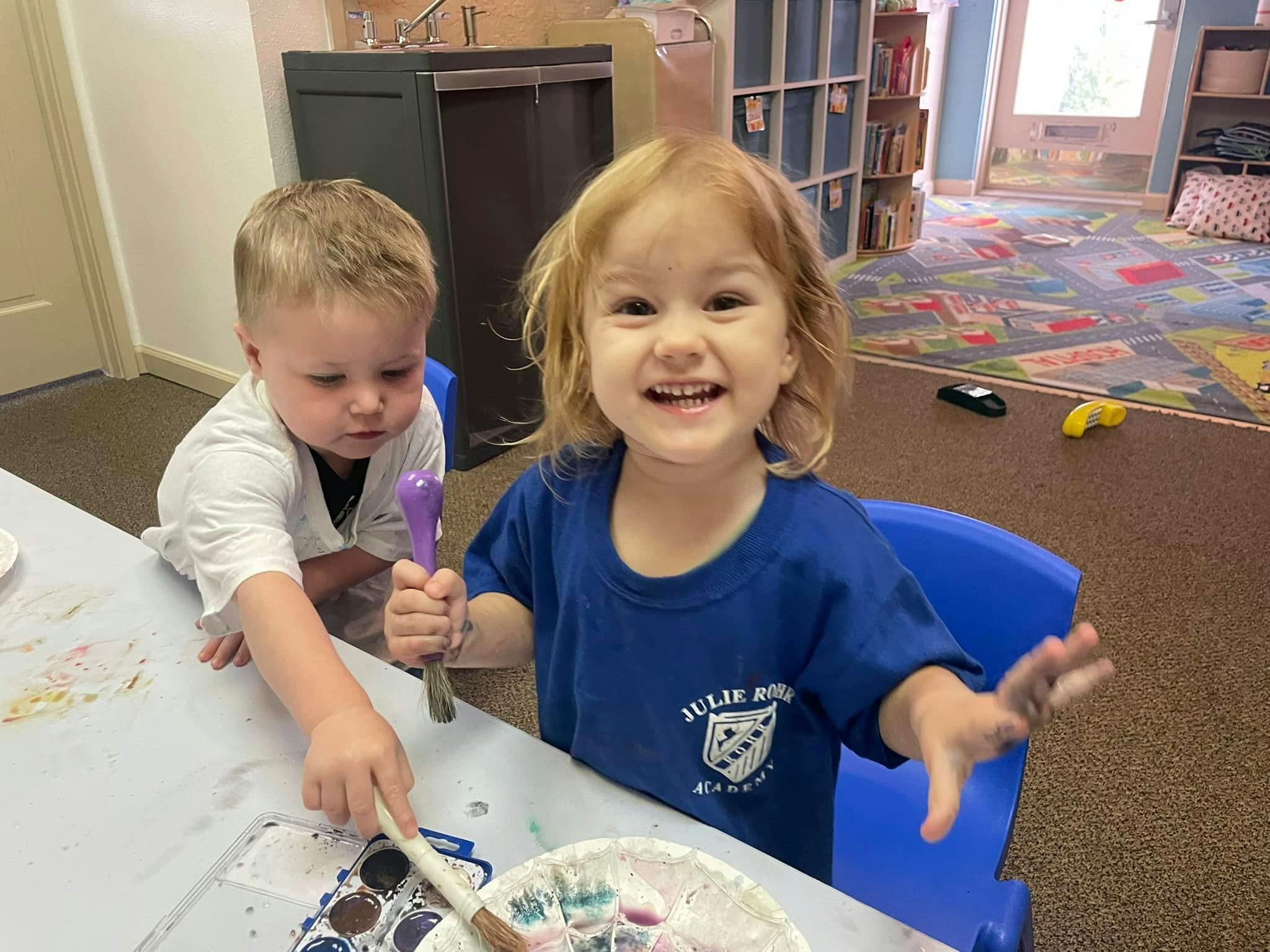 Two children painting at a table