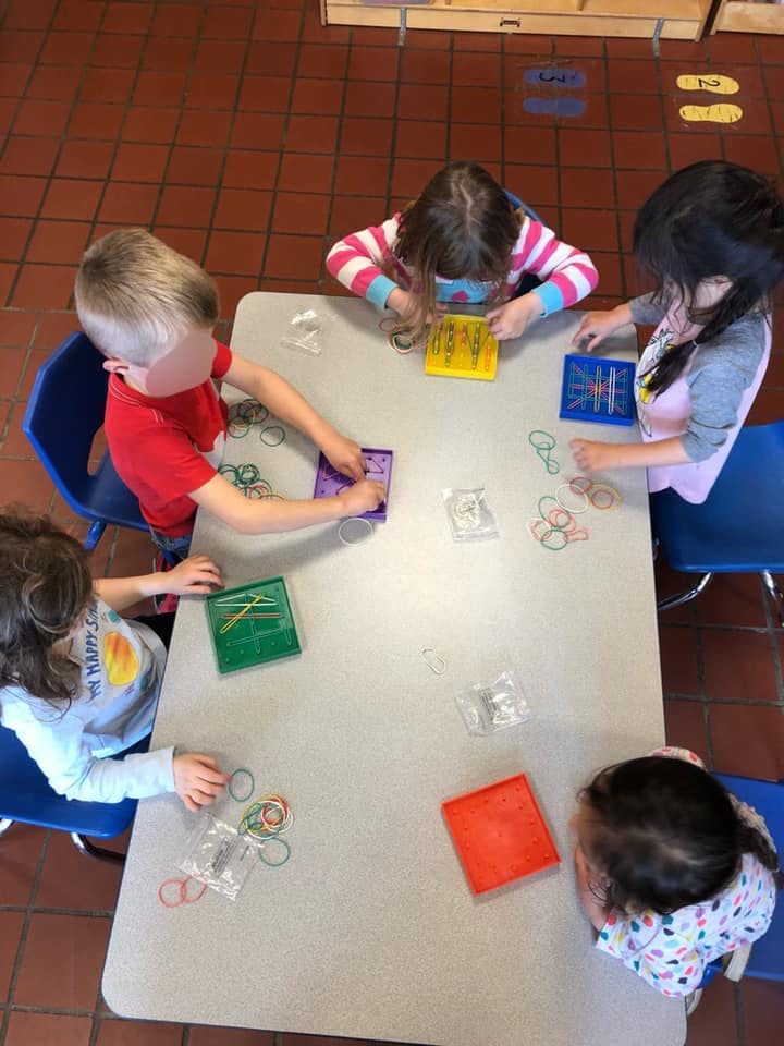 Children playing with geoboards and rubber bands at a table