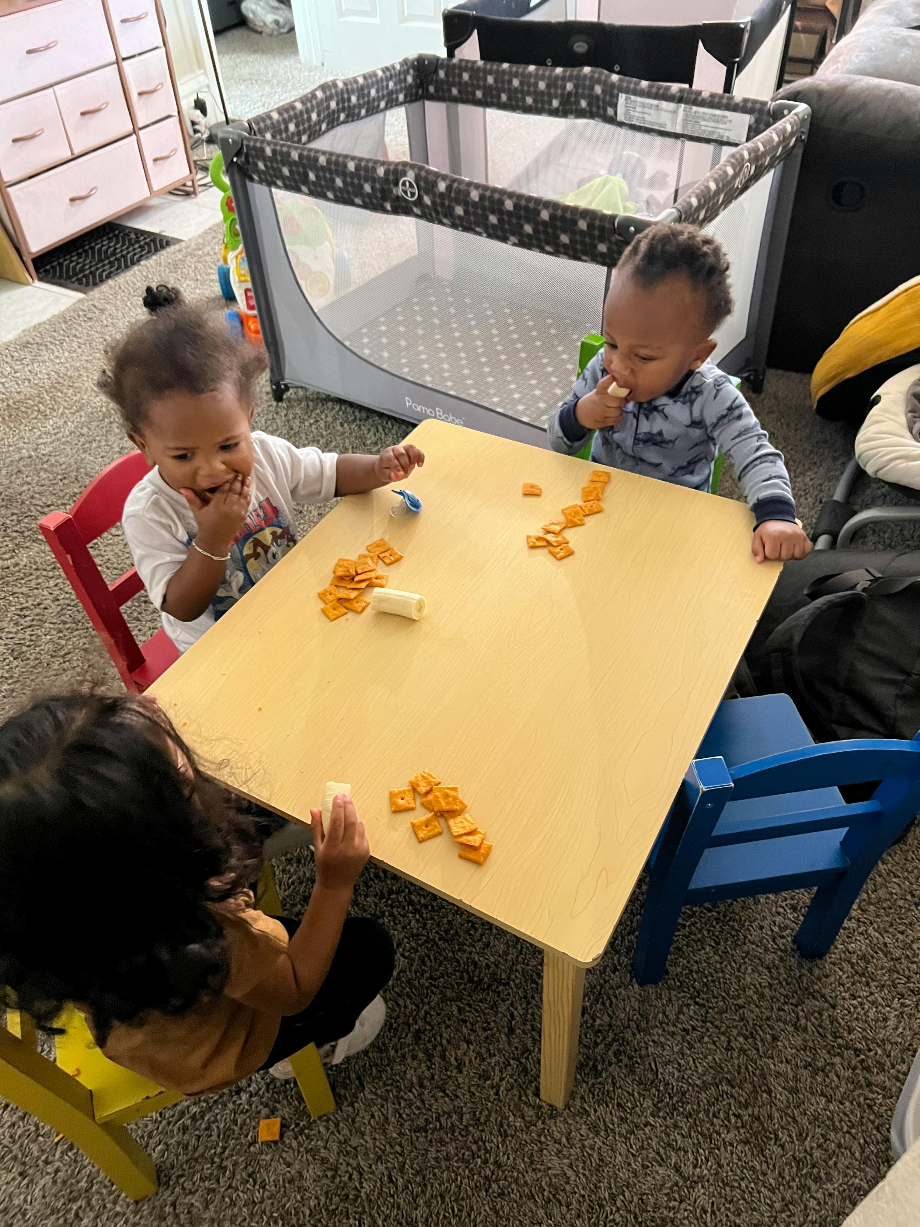Three children eating snacks at a small table