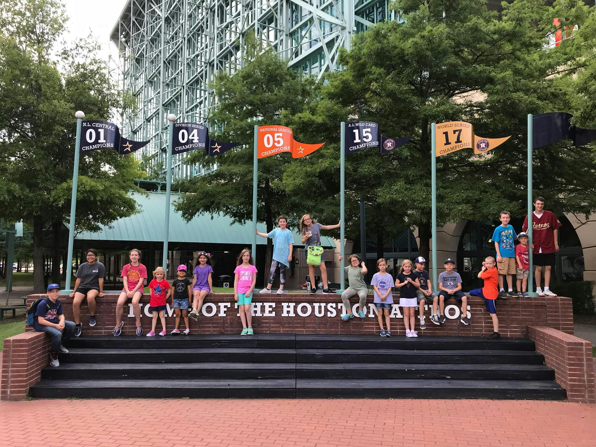 Group of people and children posing on steps with flags in background