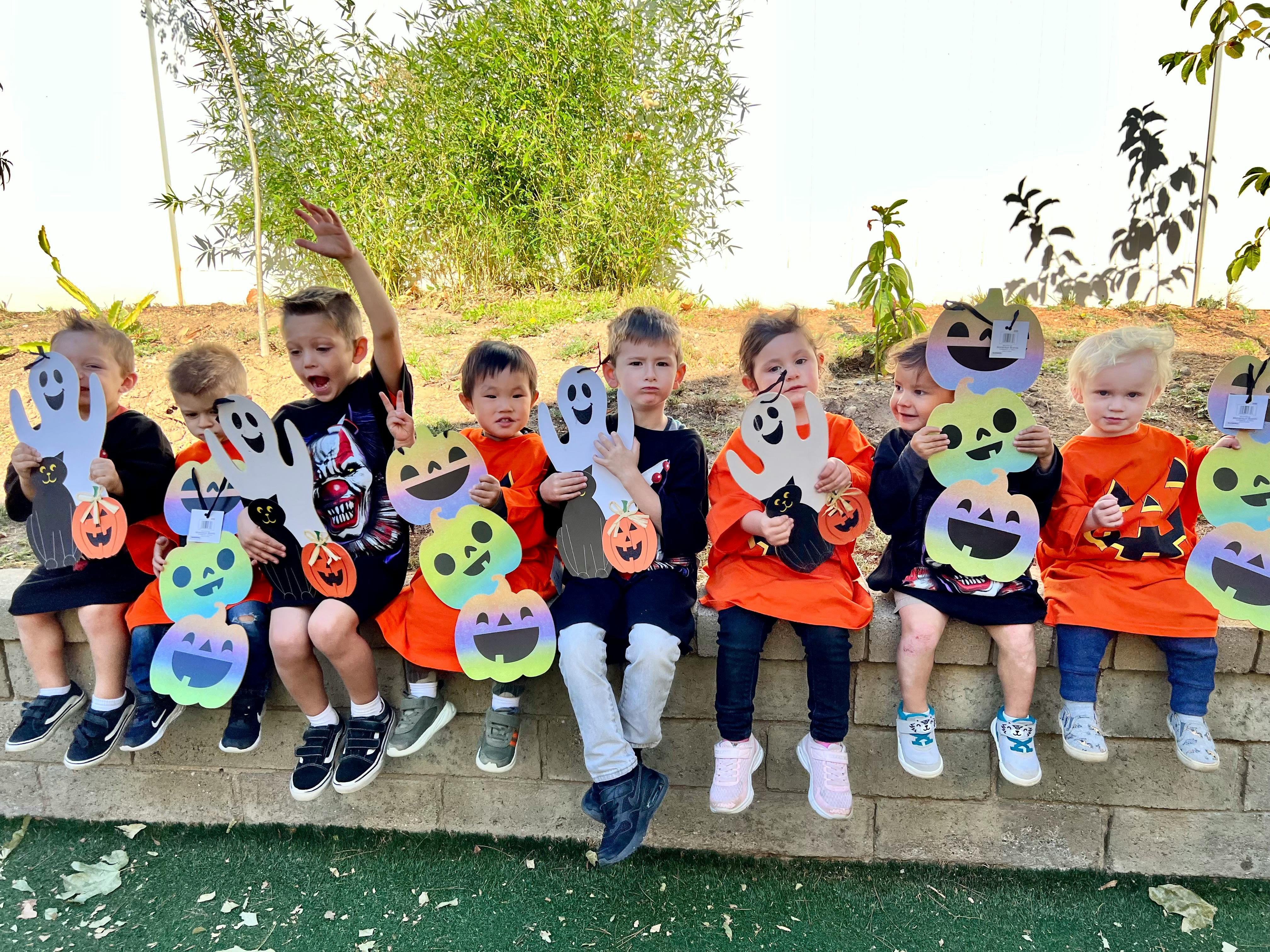 Children sitting in a row holding Halloween decorations