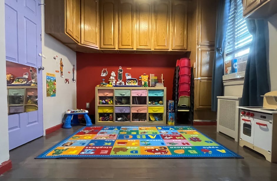 Playroom with a colorful alphabet rug, toy storage, and play kitchen