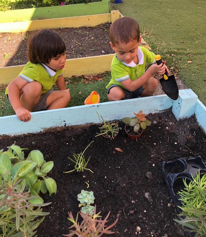 Two children planting in a raised garden bed