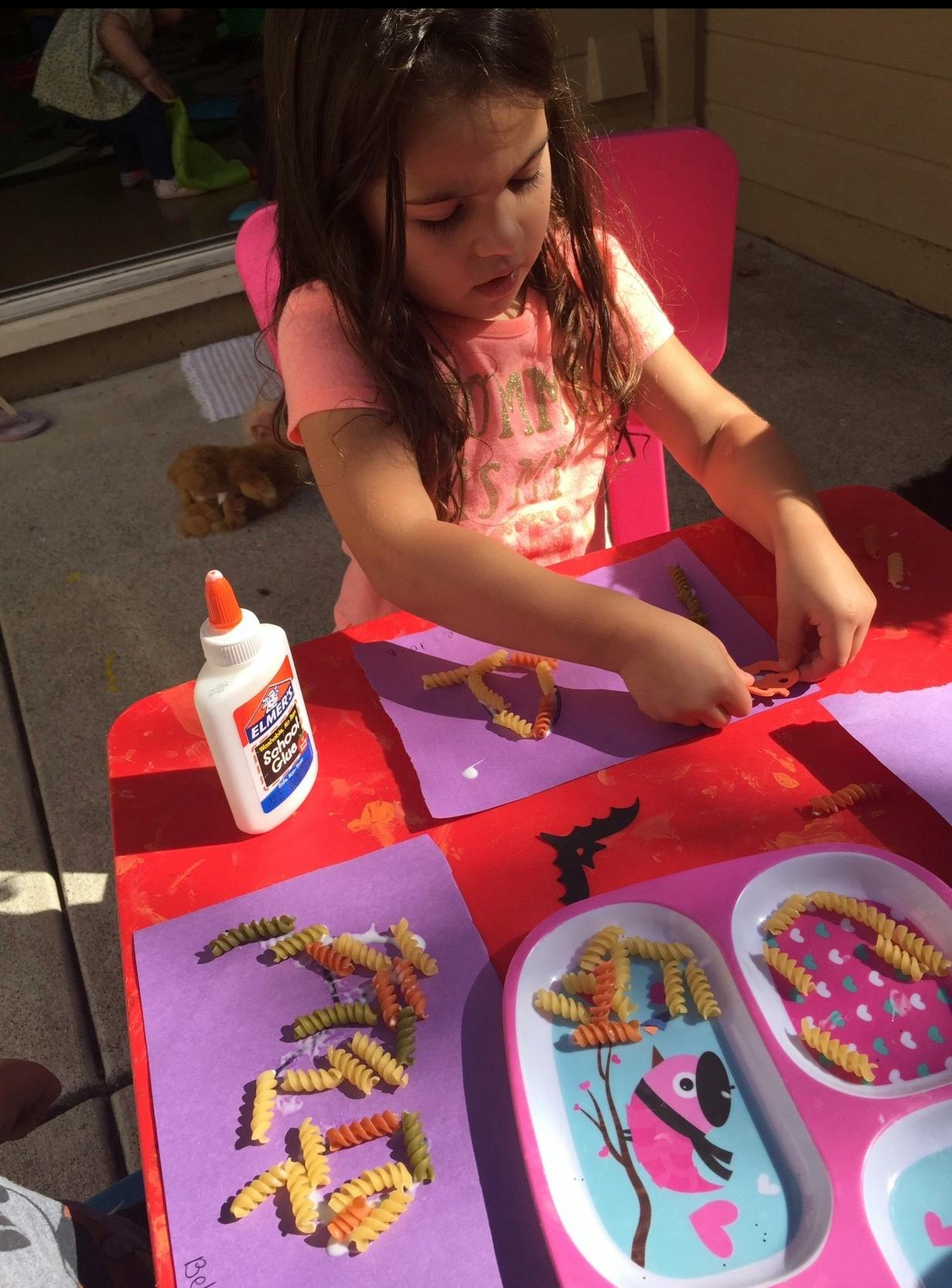 Child making crafts with pasta and glue