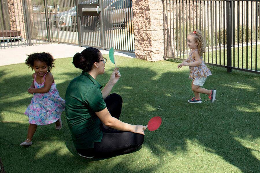 Person sitting on grass playing with two children