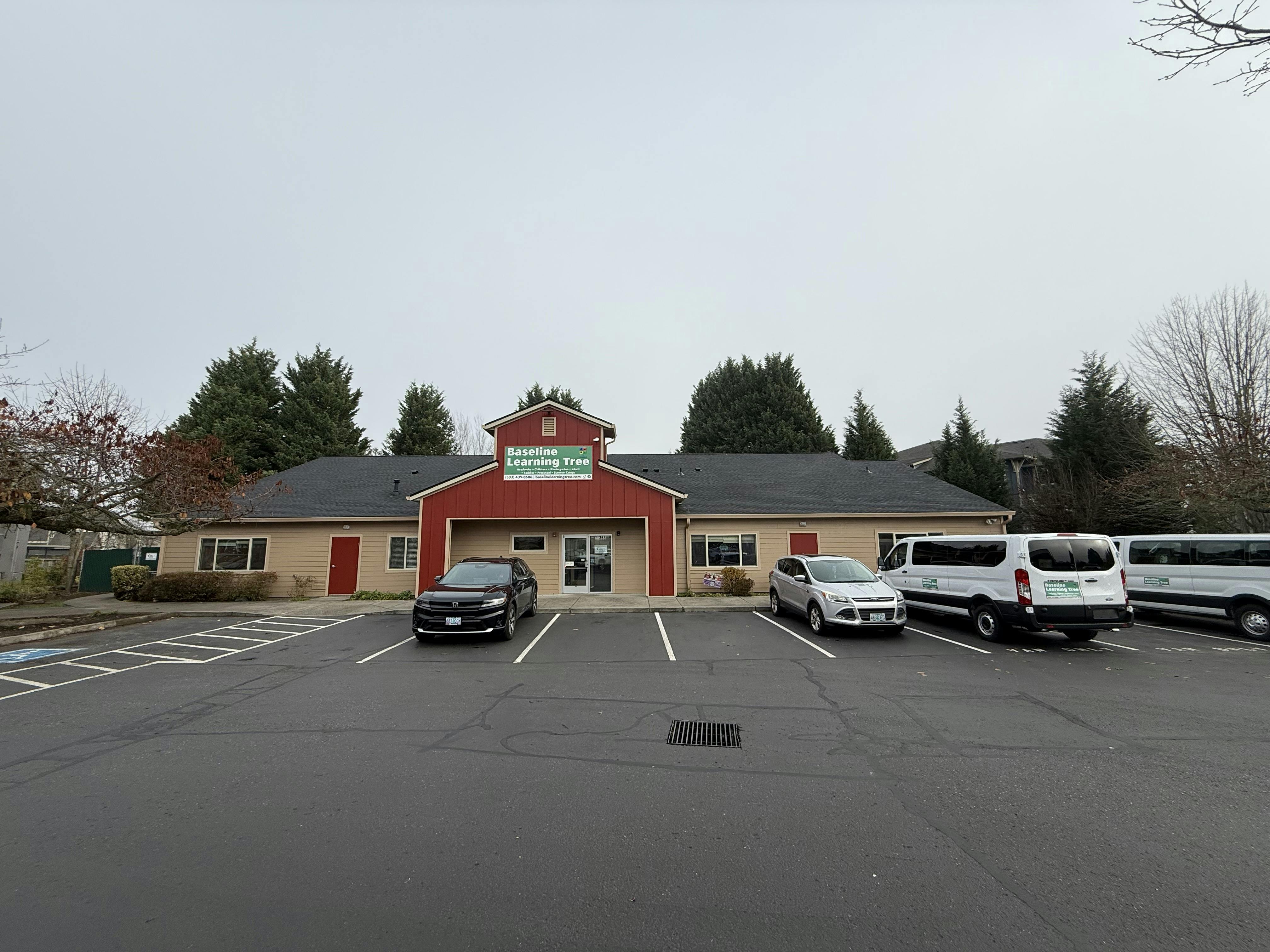 Building with a red entrance and a parking lot with cars