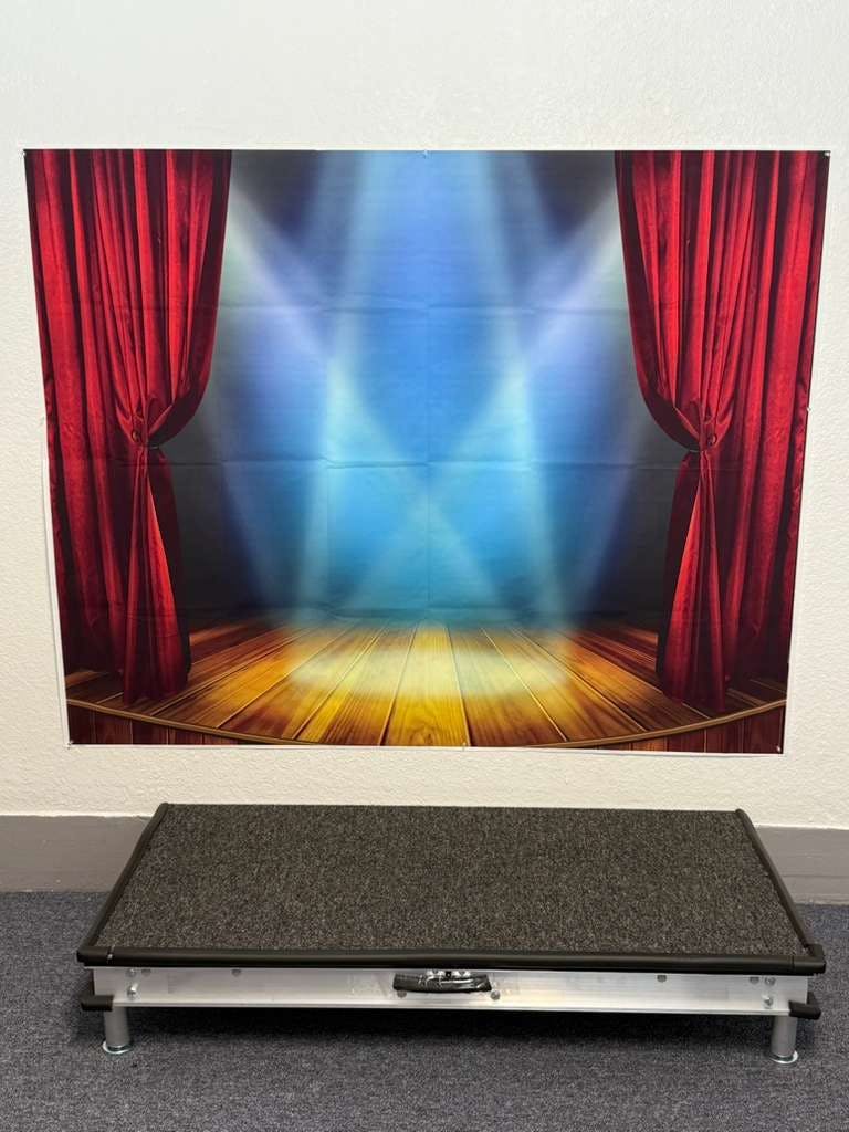 Stage backdrop with red curtains and spotlight effect above a small stage
