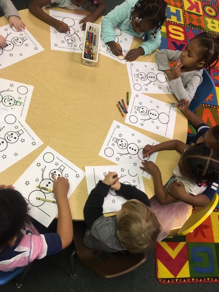 Children coloring snowman pictures at a table