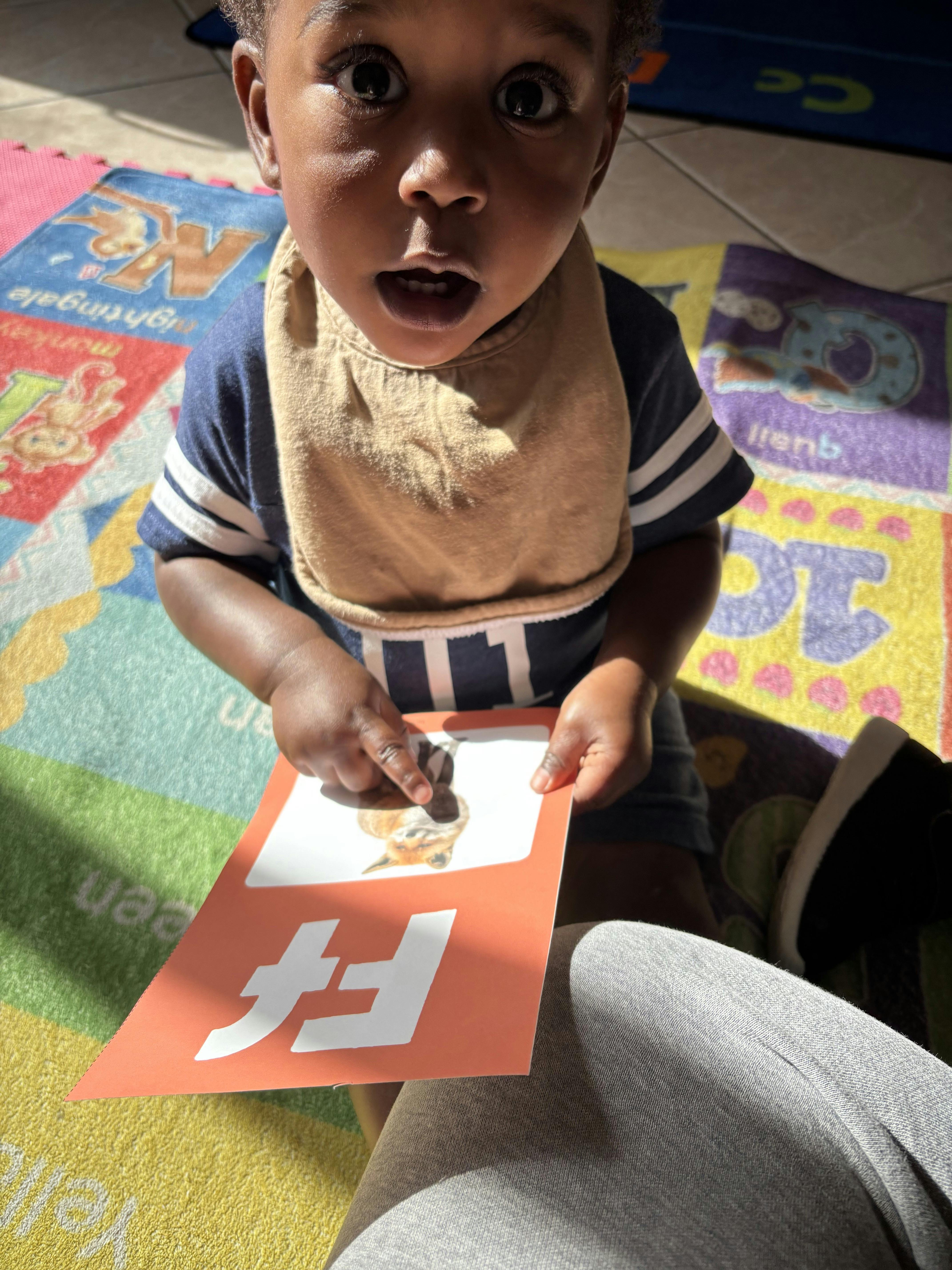 Child pointing at a flashcard with the letter F