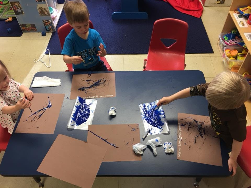Three children painting at a table