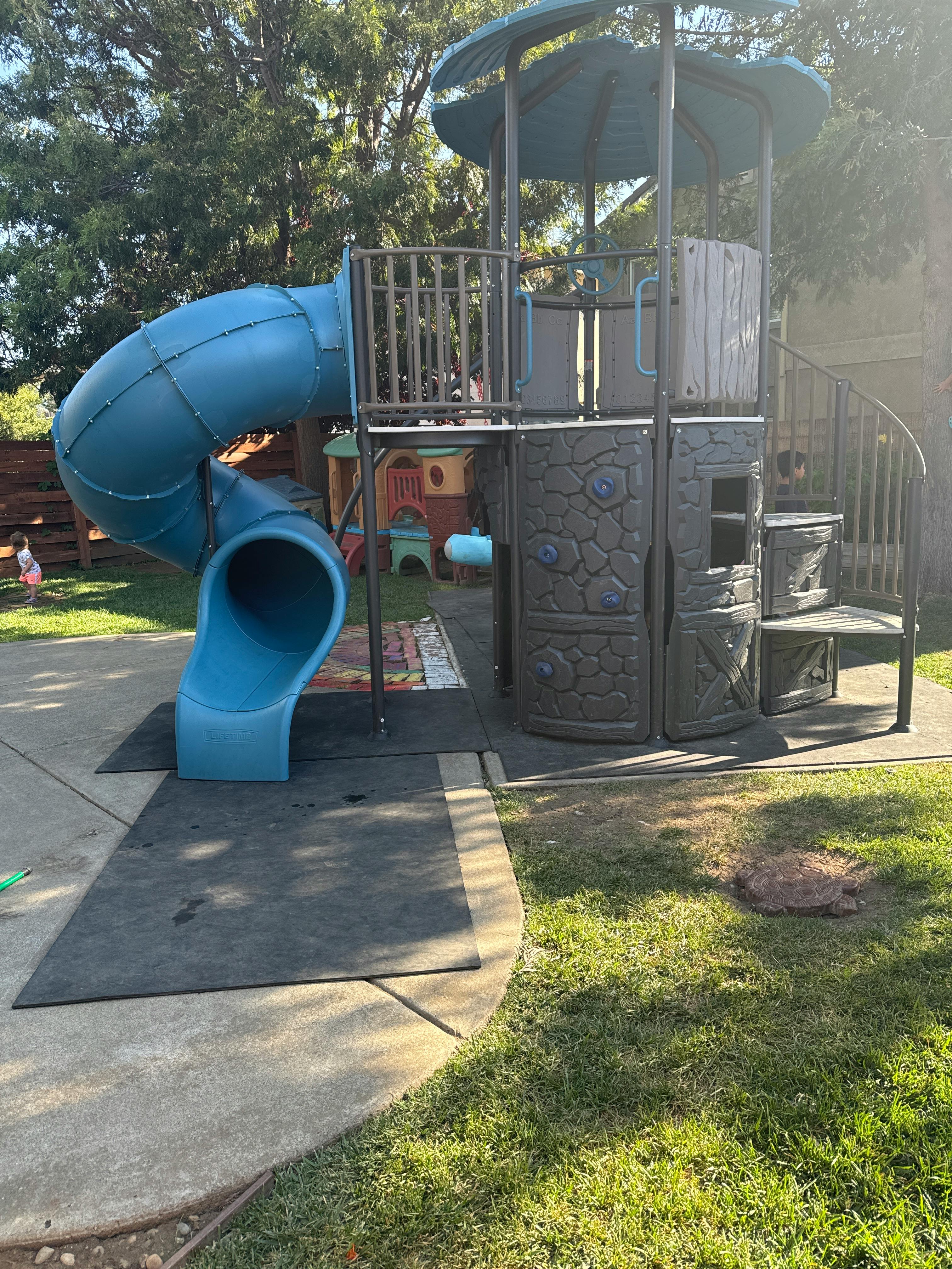 Playground structure with a blue slide and climbing areas