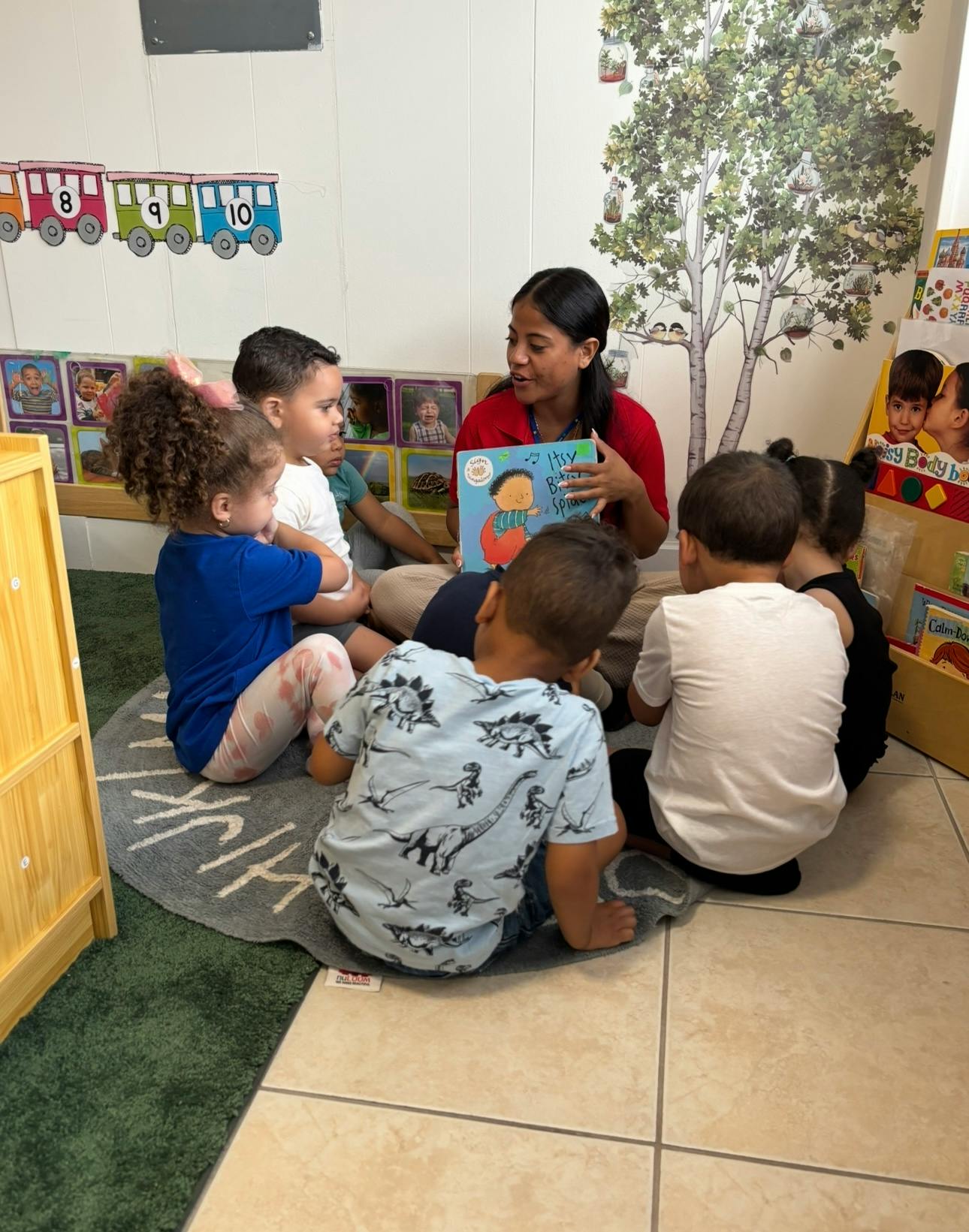 Person reading a book to a group of children sitting on the floor