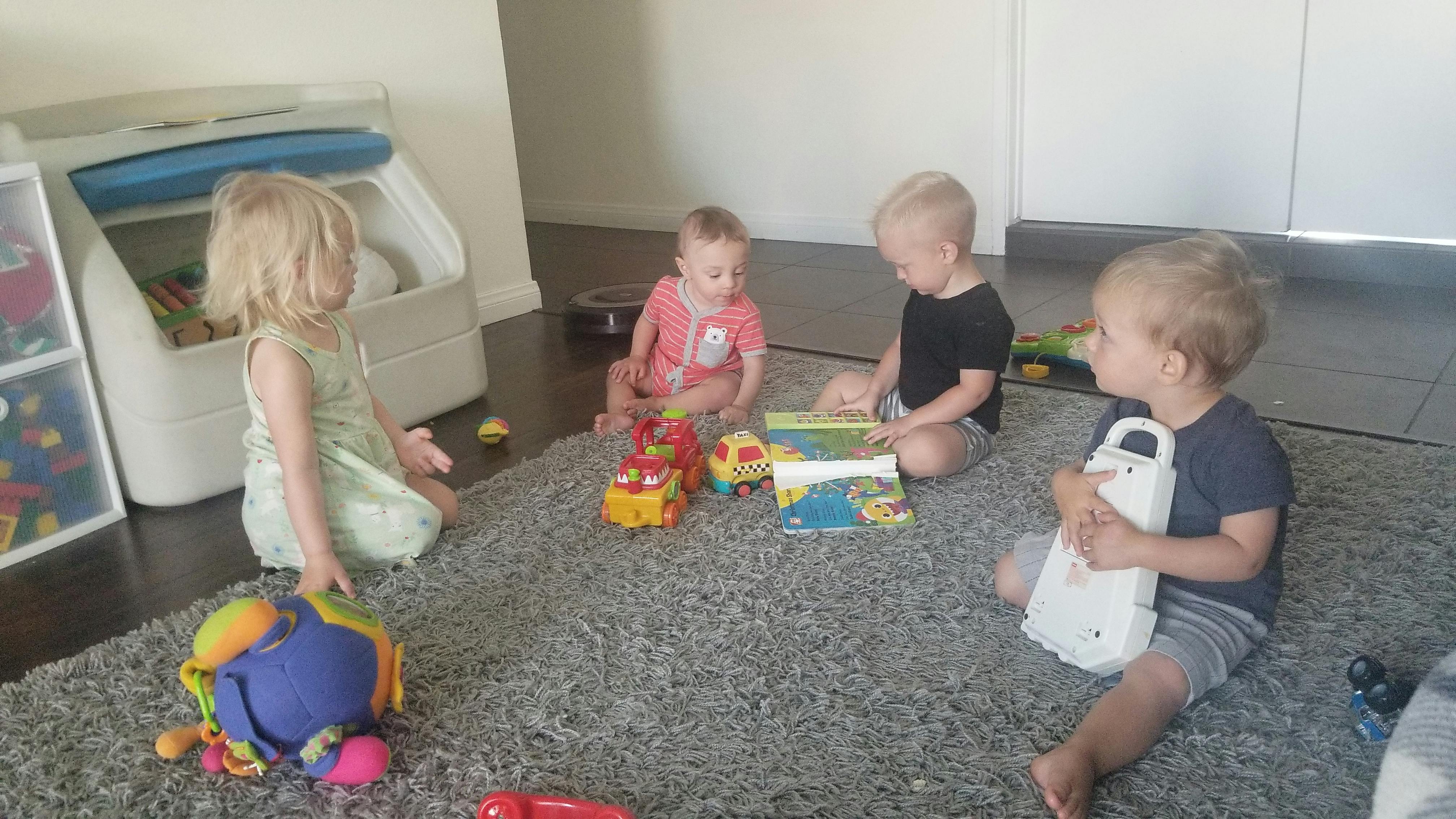 Four children playing with toys on a rug