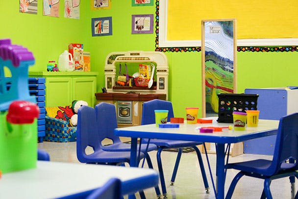 Playroom with small tables and chairs, toy kitchen, and colorful walls