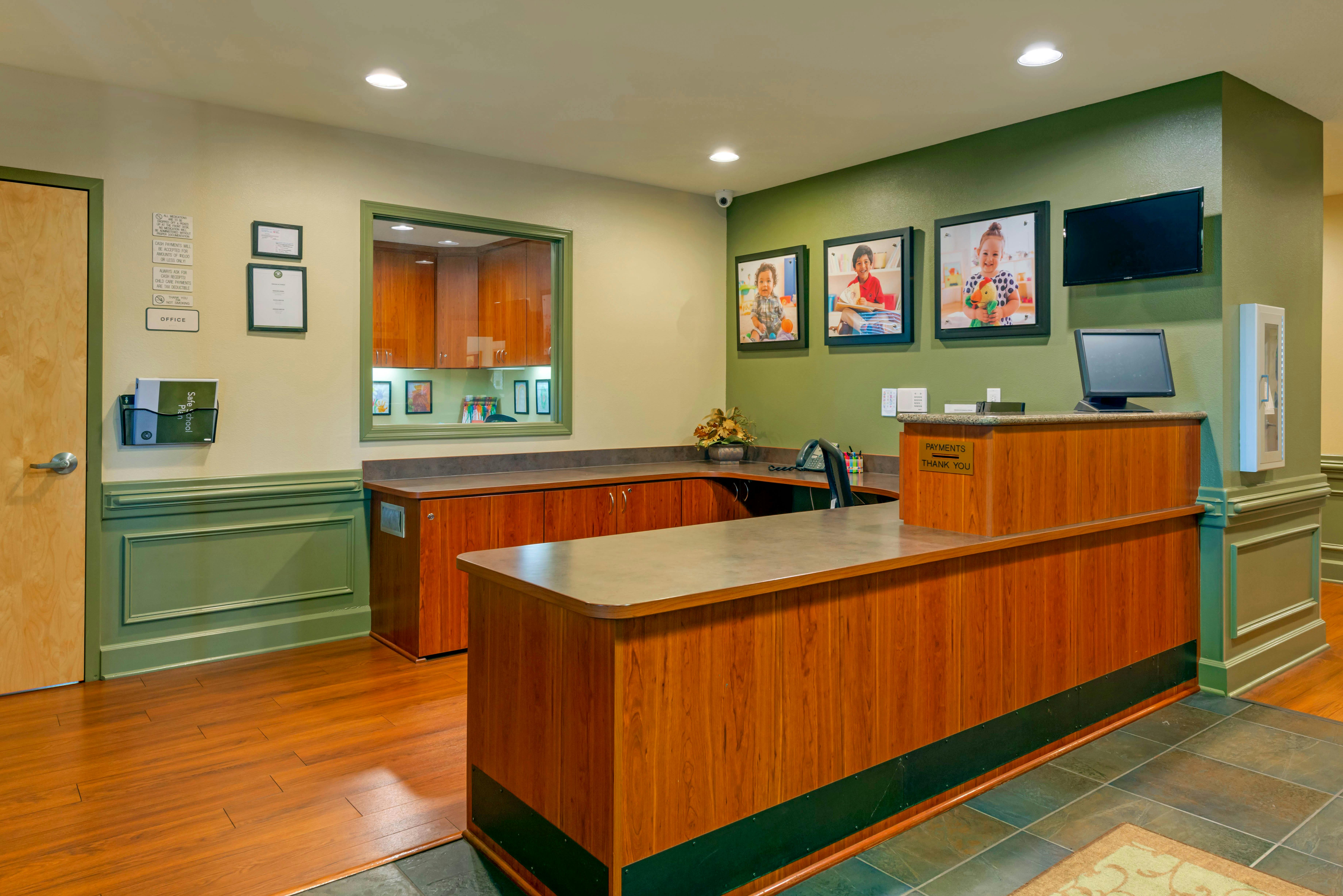 Reception desk with multiple framed pictures of children on the wall