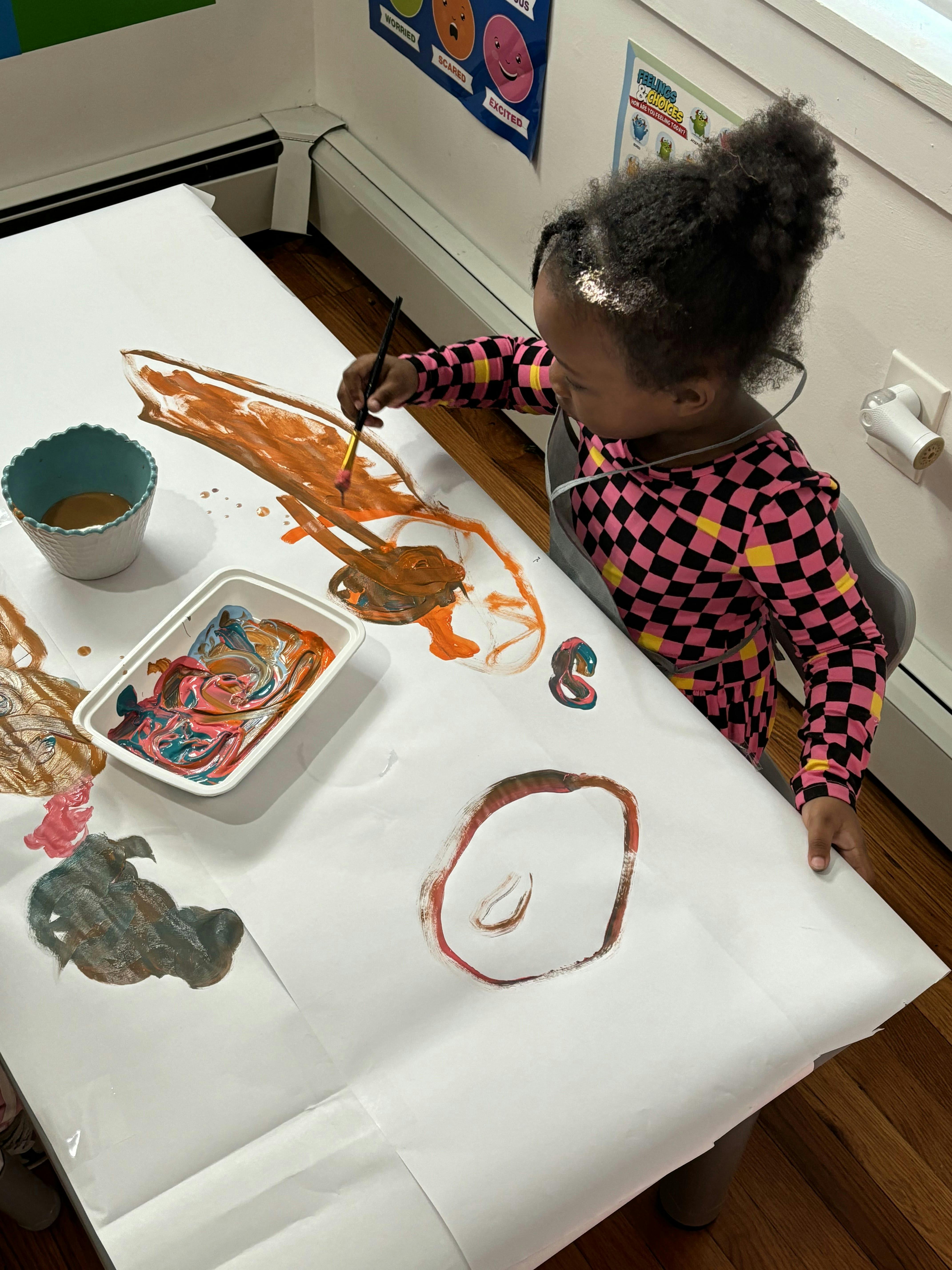 Child painting with a brush on a large piece of paper