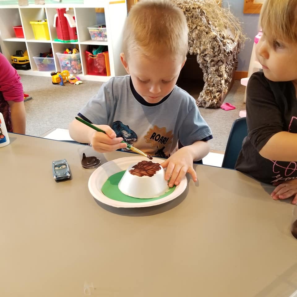 Child painting a craft on a paper plate