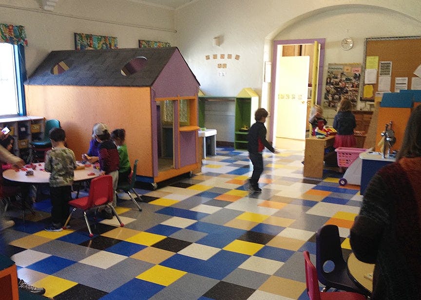 Children in a classroom with a playhouse and activity area