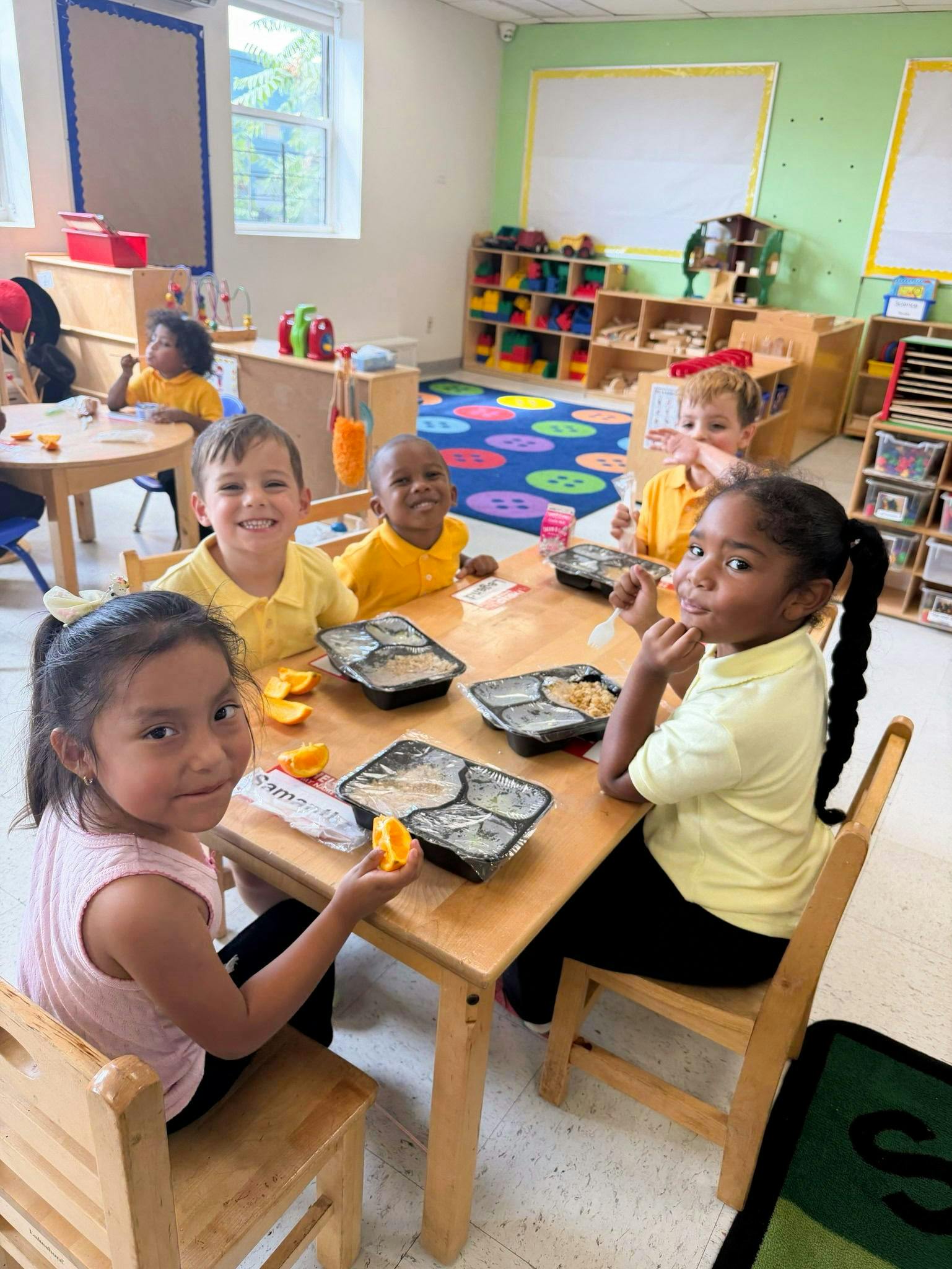 Group of children eating lunch at tables in a classroom