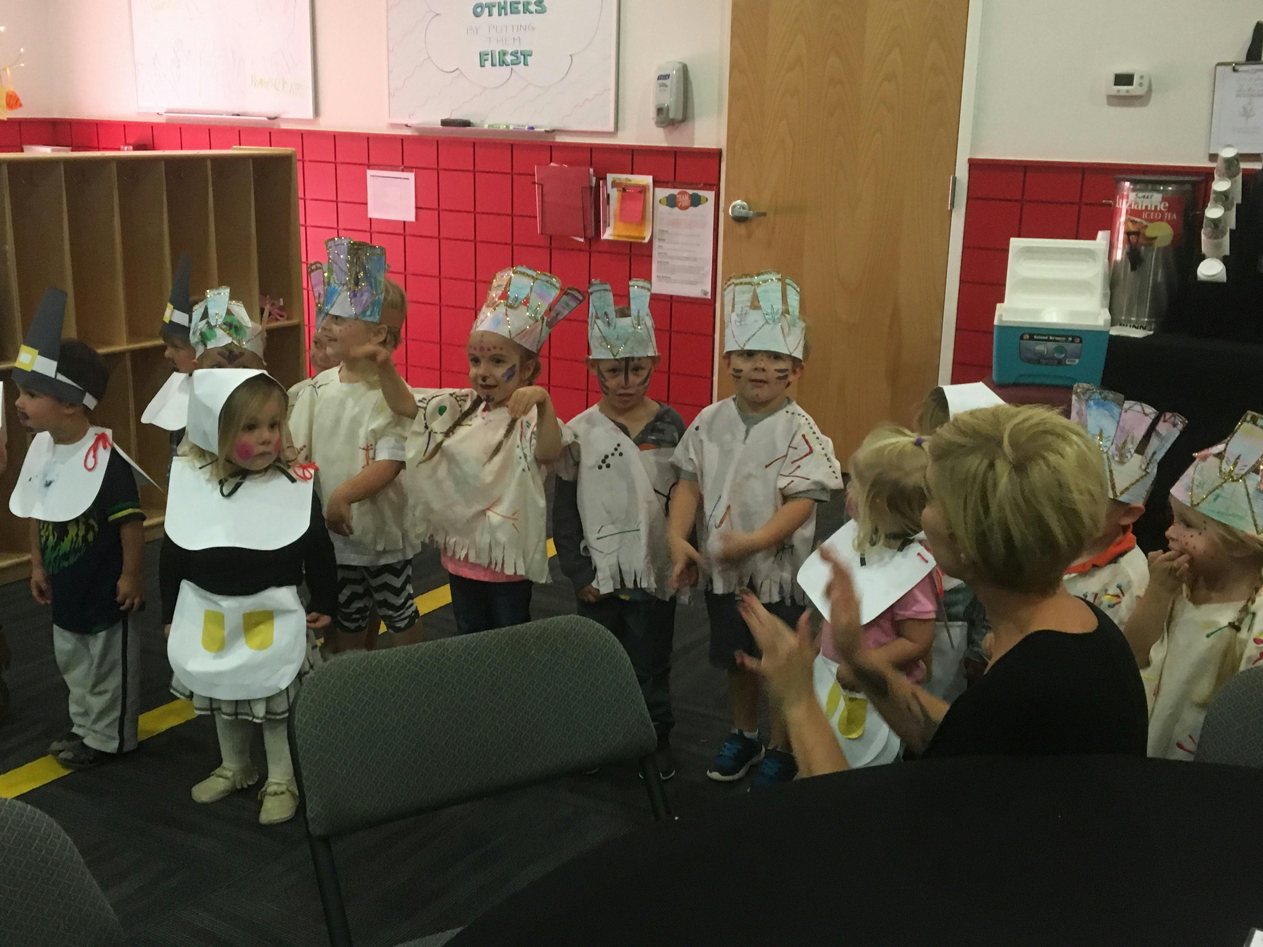 Children in costumes with a person clapping