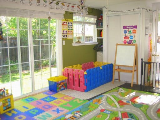 Playroom with colorful floor mats, playpen, and easel