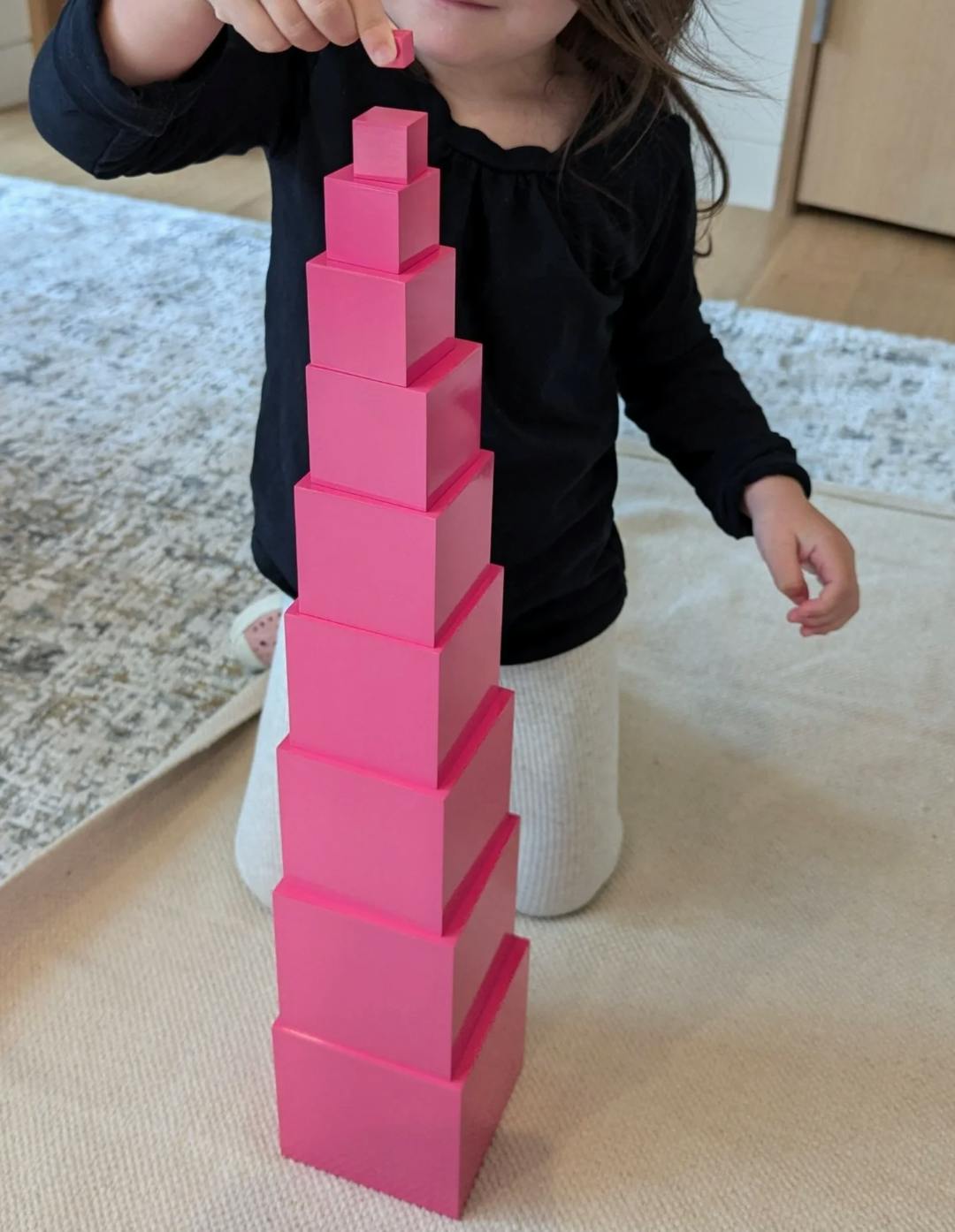 Child placing a block on a tower of stacked cubes