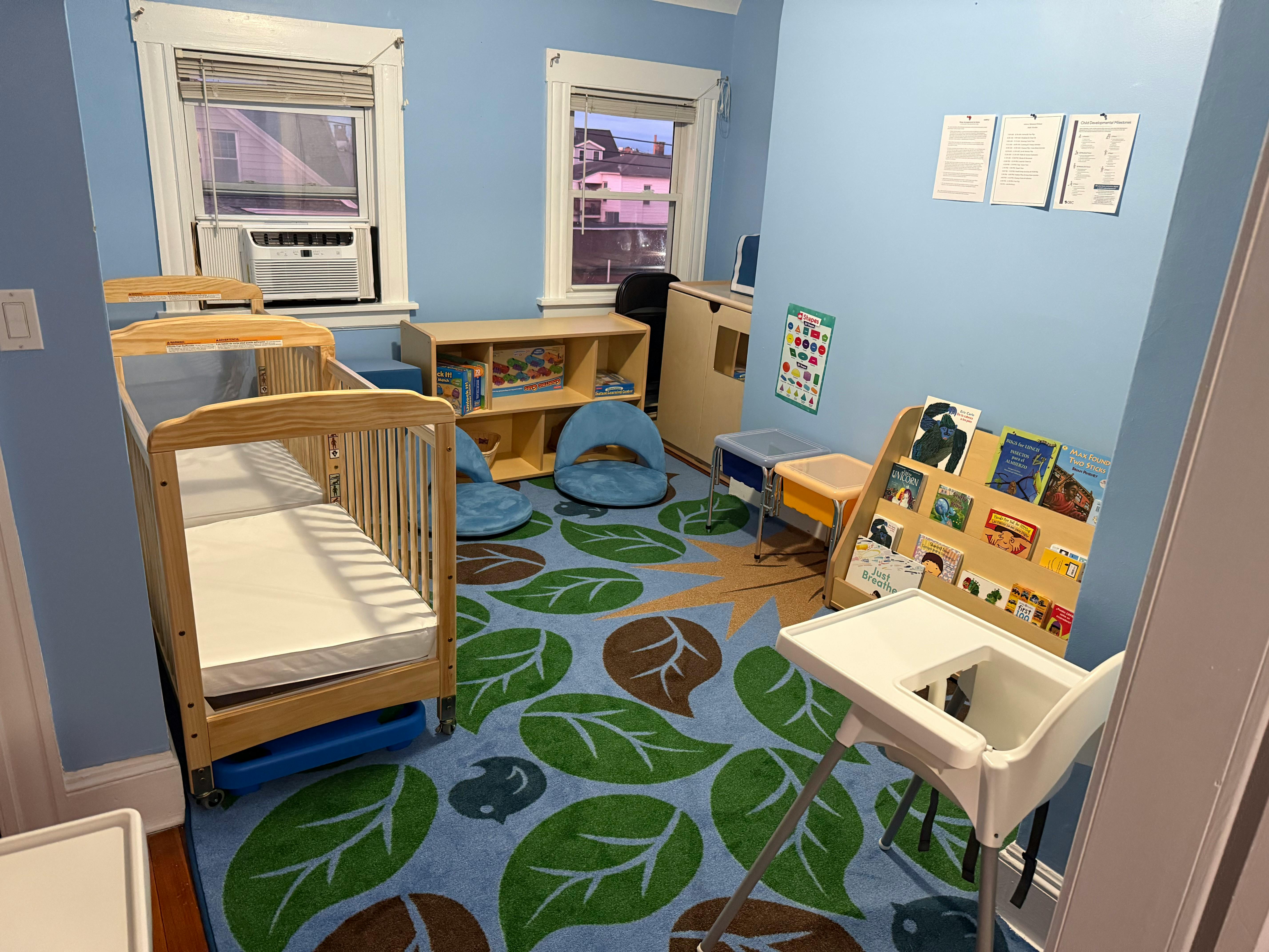 Nursery room with a crib, high chair, and leaf-patterned rug
