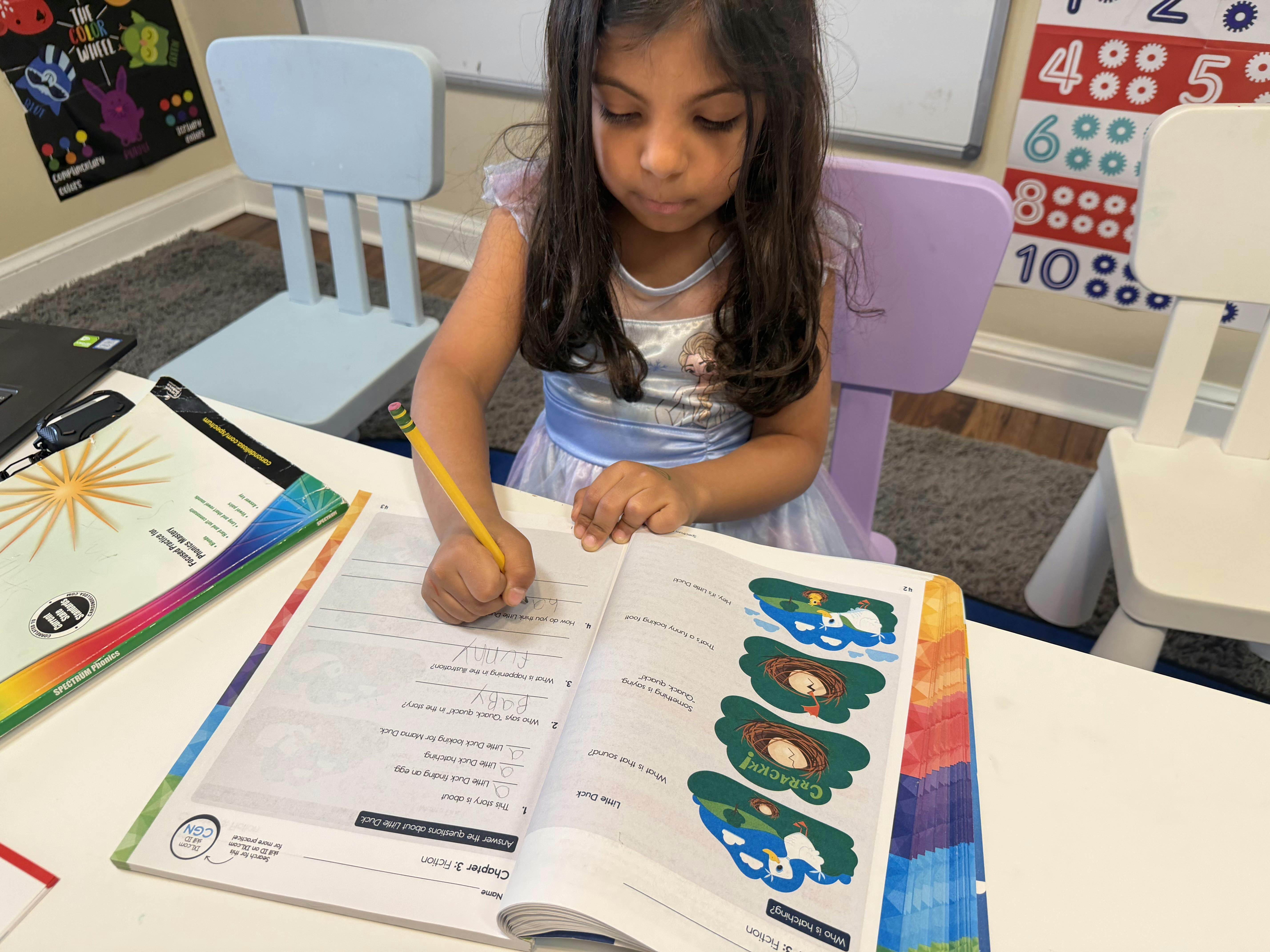 Child writing in a workbook at a desk with a pencil