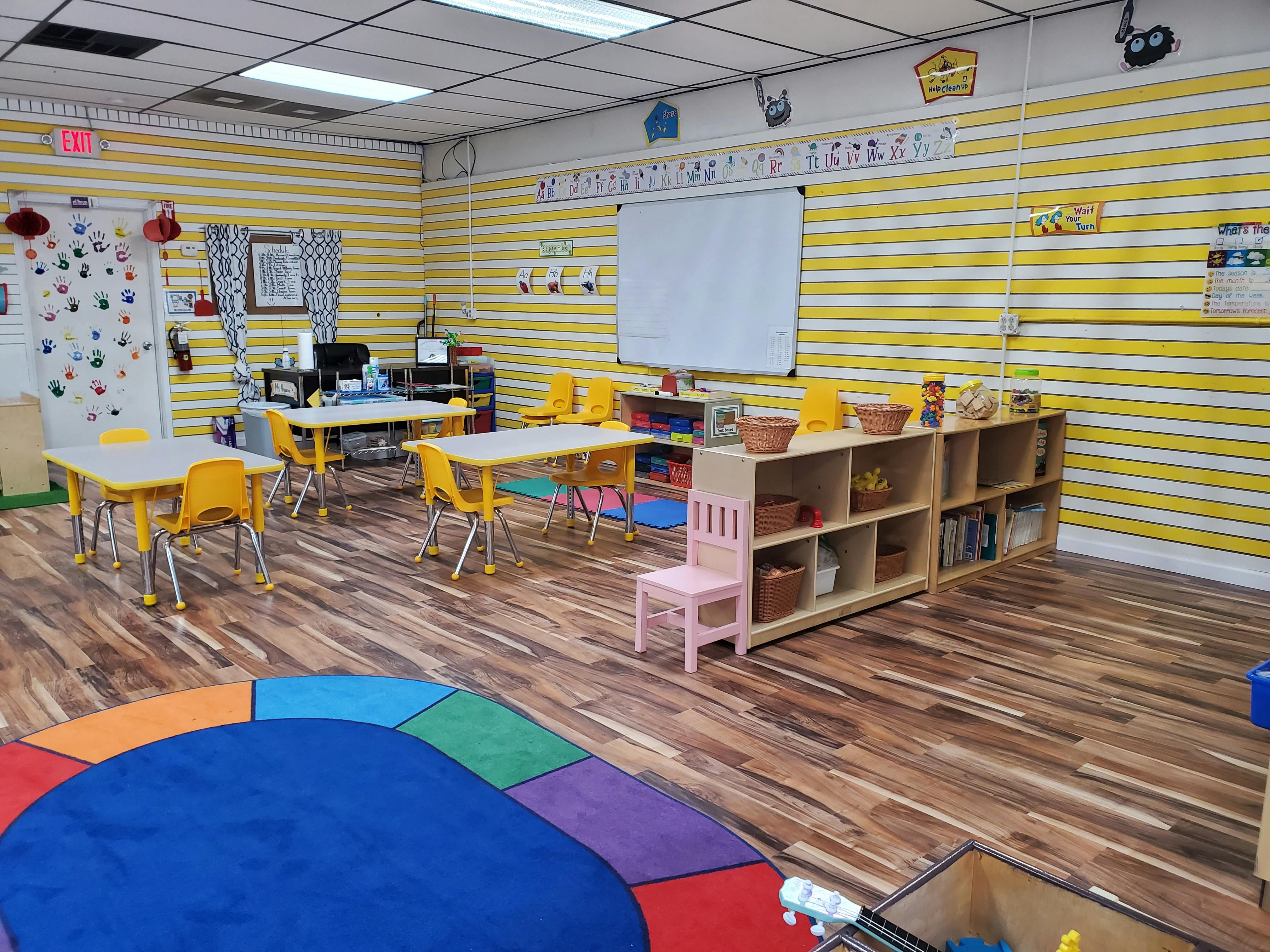 Classroom with small tables and chairs, shelves, and a colorful rug