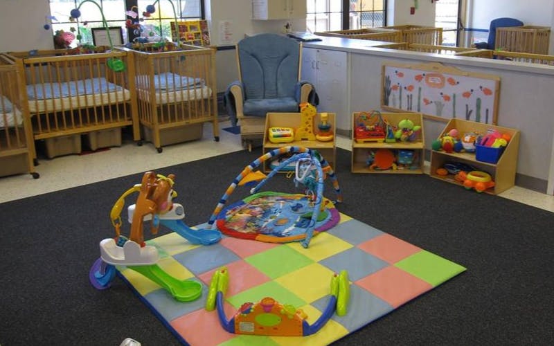 Cribs, playmat, and infant toys in a childcare room
