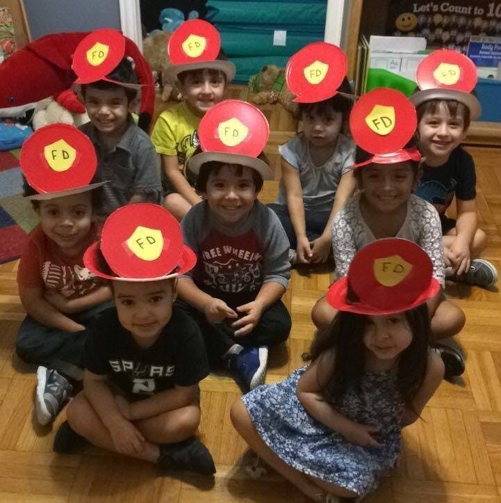 Group of children wearing red paper firefighter hats
