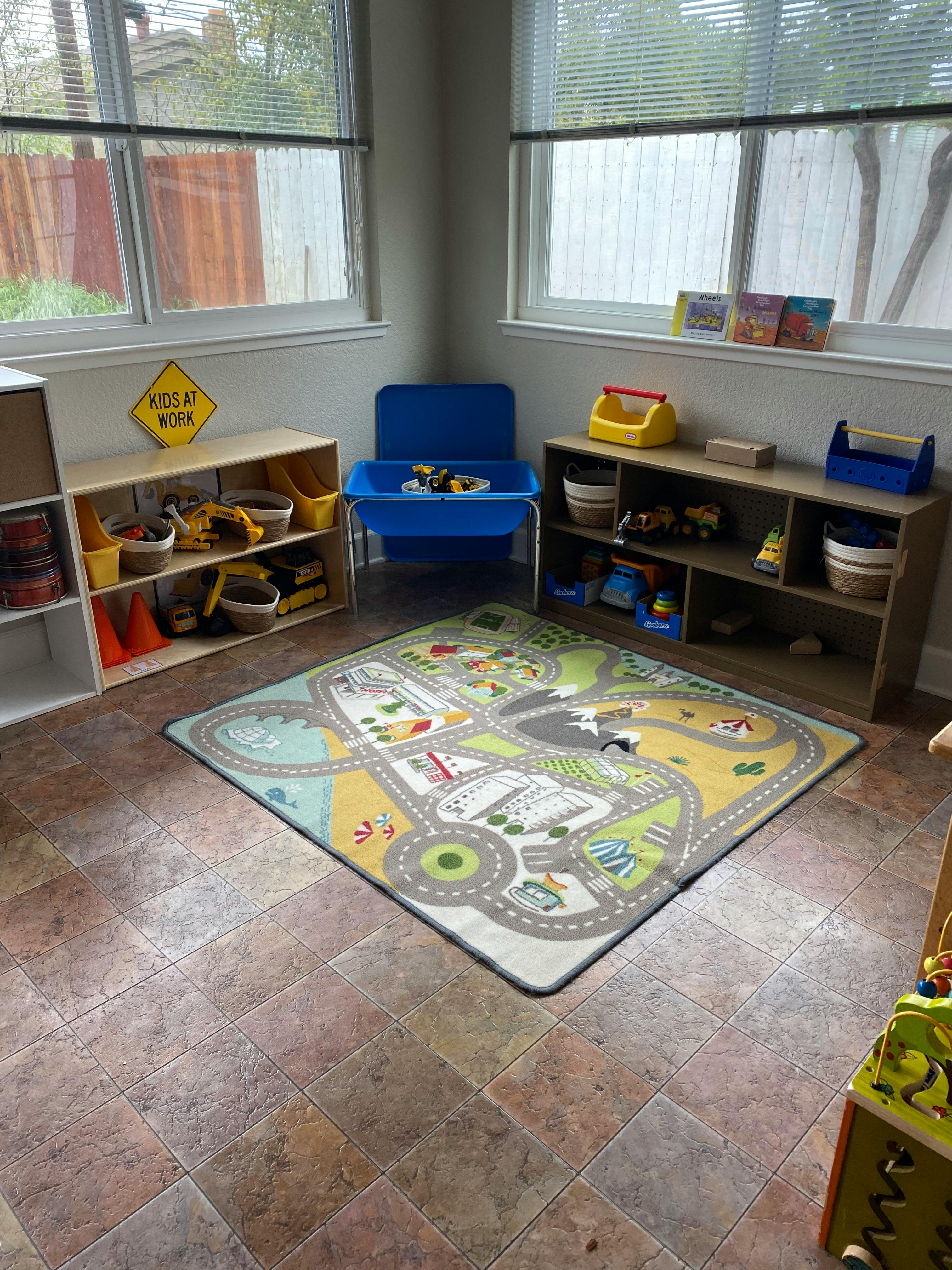 Playroom with a road map rug, shelves with toys, and a blue sensory table
