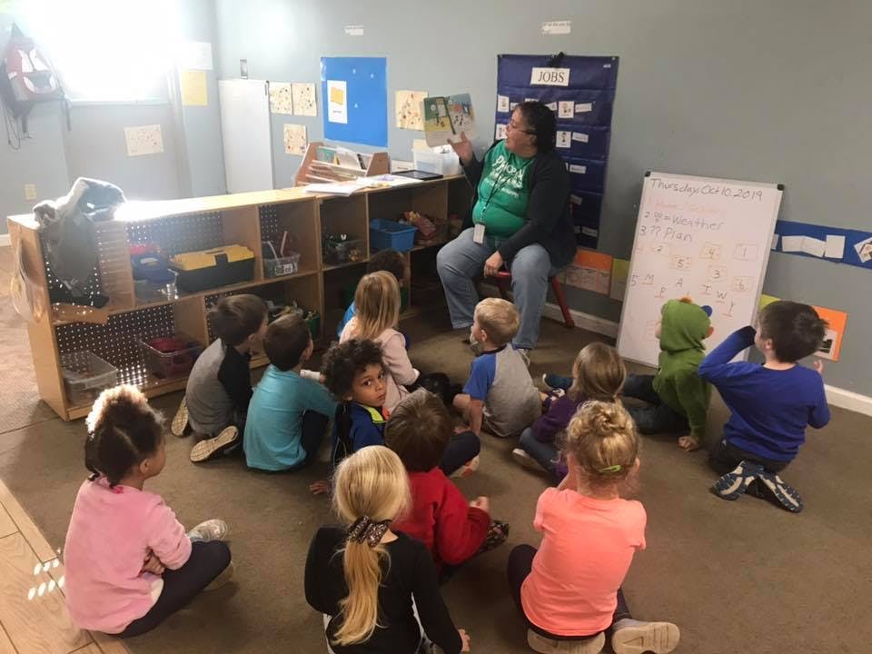 Adult reading to a group of children in a classroom