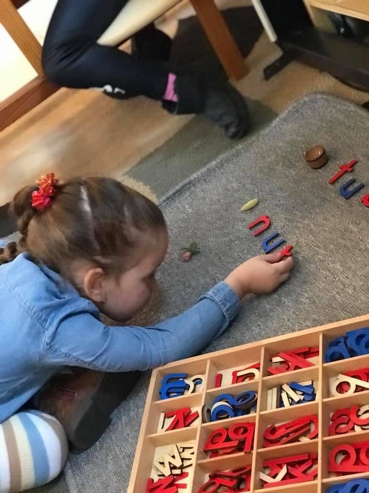 Child playing with letter tiles on a rug