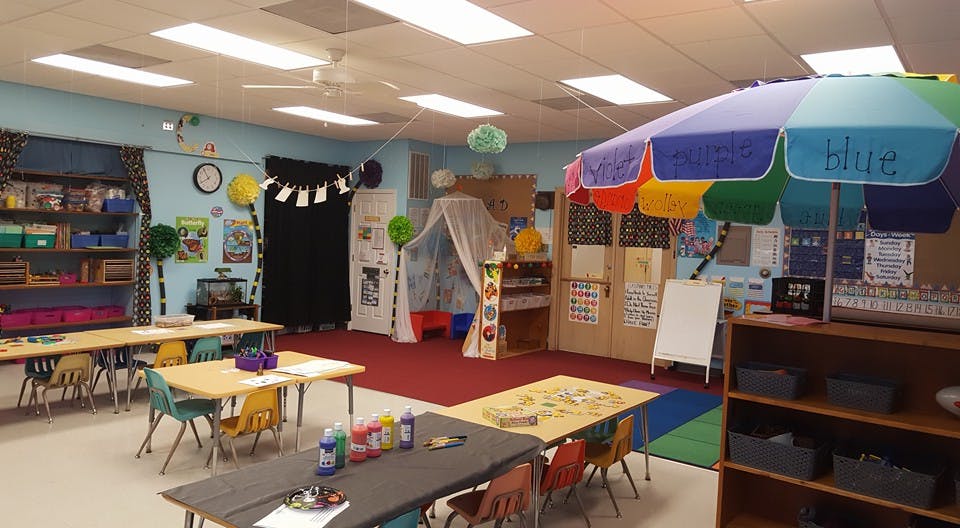 Classroom with small tables and chairs, a canopy, and a colorful umbrella