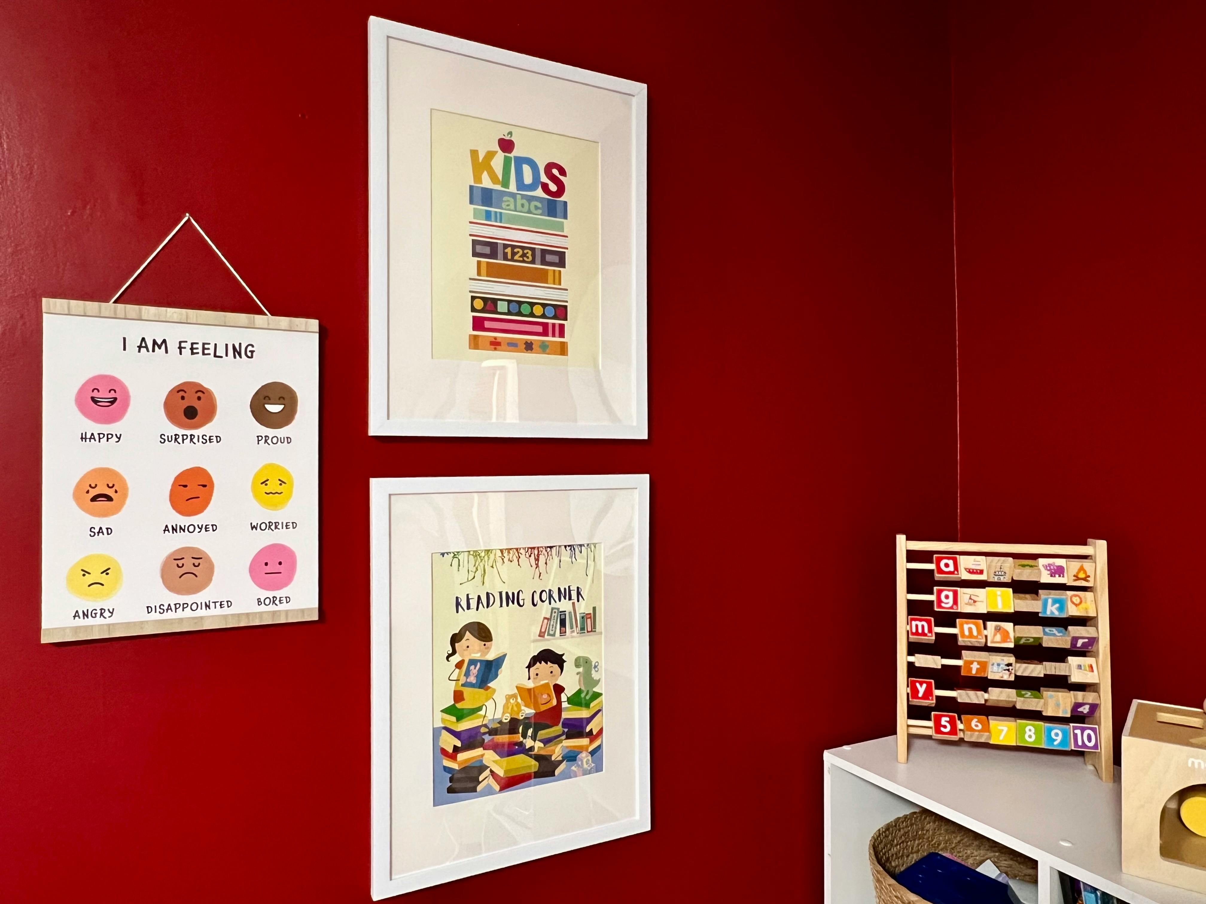 Three framed pictures and a hanging chart on a red wall