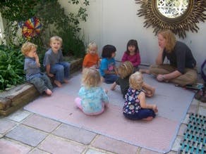 Adult and children sitting on a mat outdoors