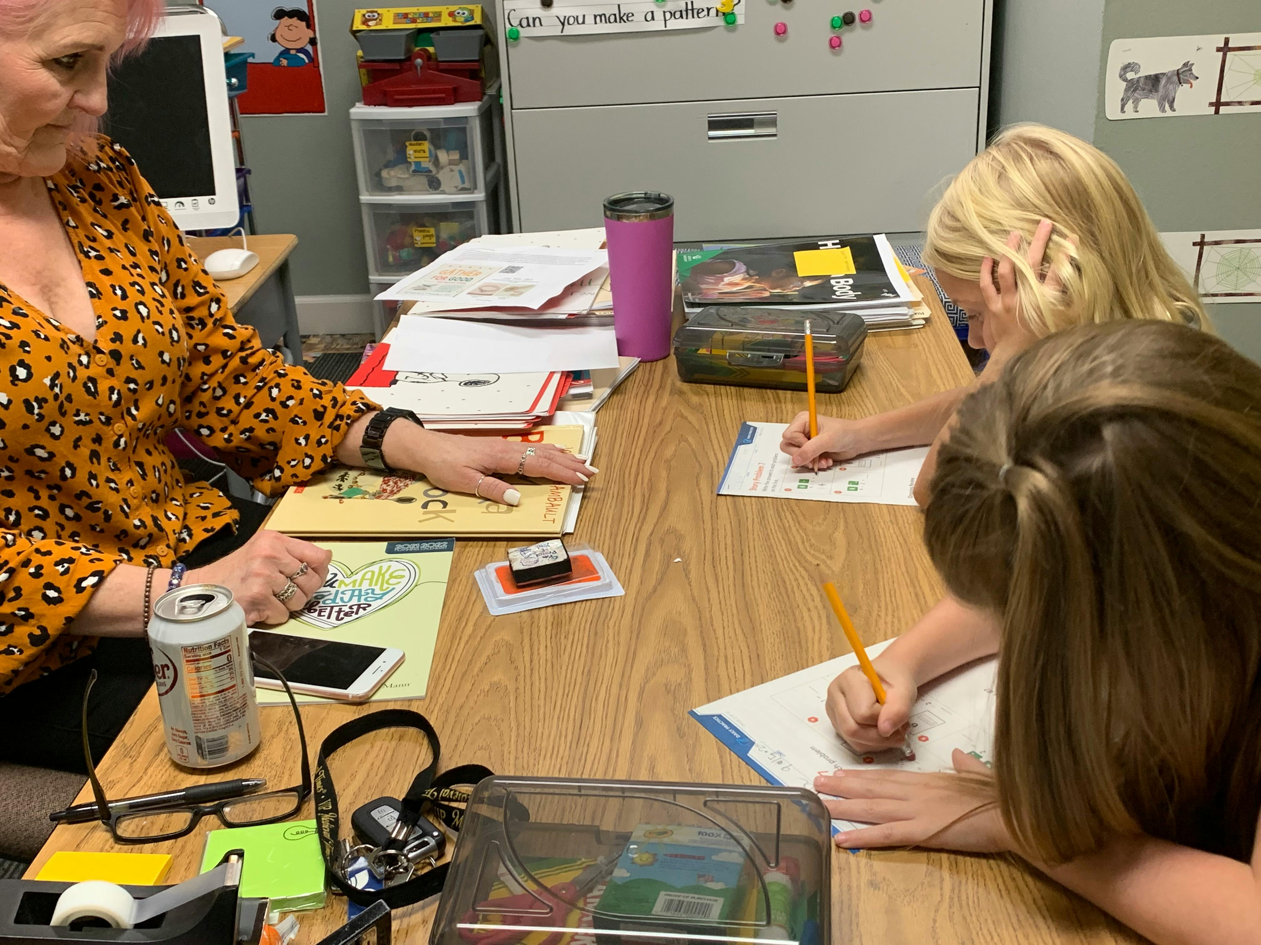 Adult and two children writing at a table