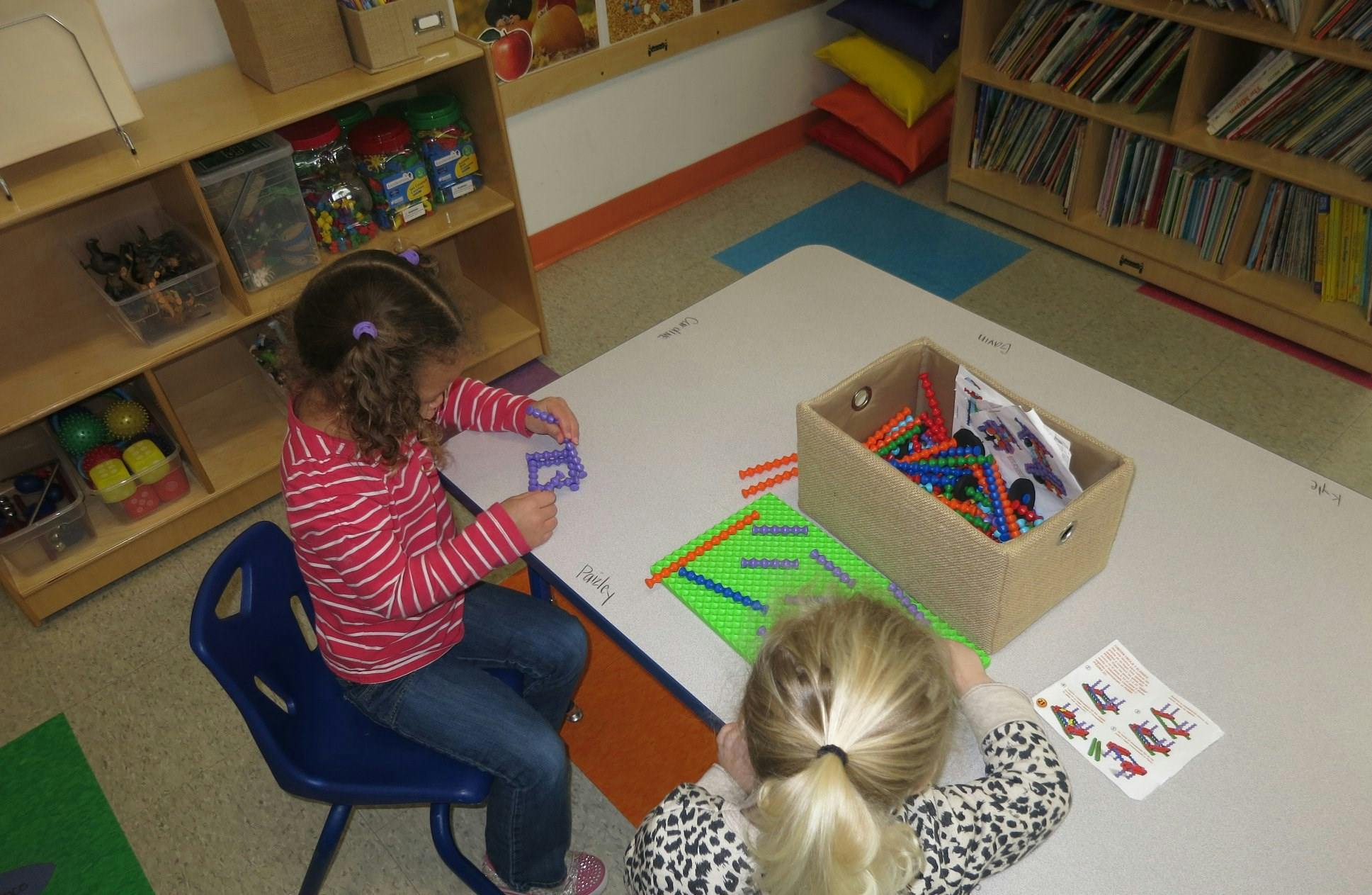 Two children at a table with craft supplies in a classroom