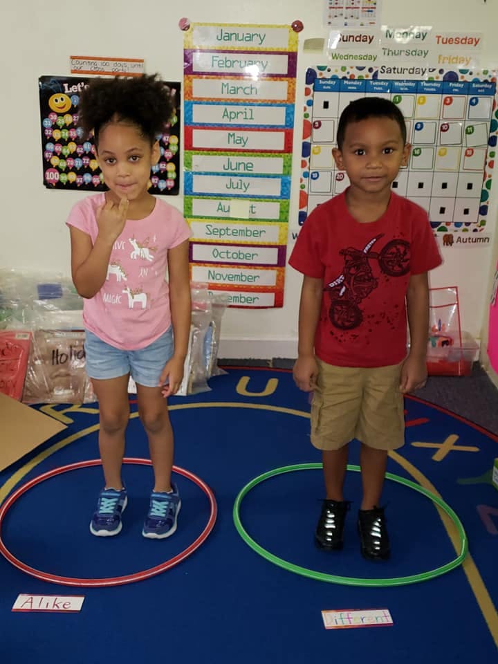 Two children standing in hula hoops in a classroom