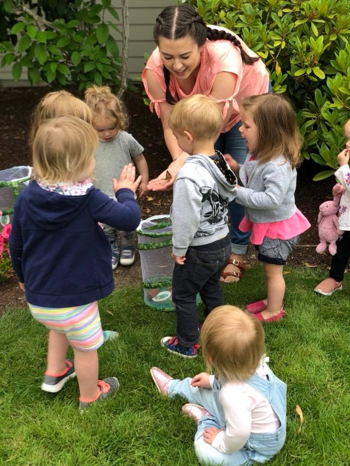Adult and children gathered around a butterfly habitat