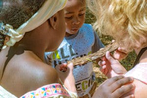 Two people and a child looking at a piece of wood