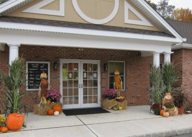 Building entrance decorated with pumpkins, scarecrows, and fall plants