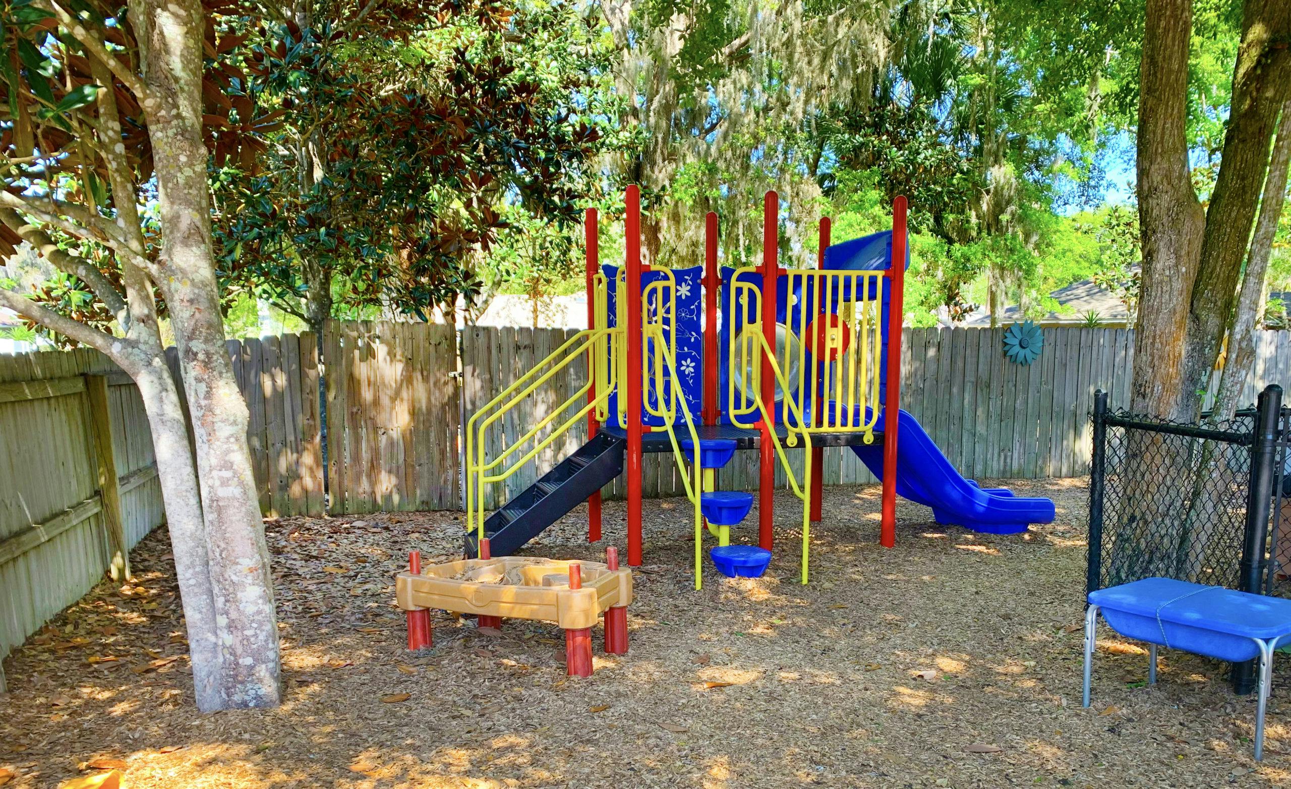 Playground with a red and blue playset featuring a slide and stairs
