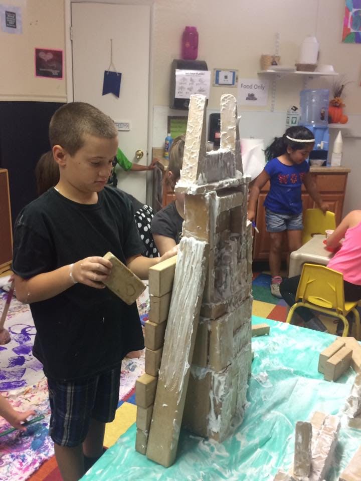 Child building a structure with blocks and white material
