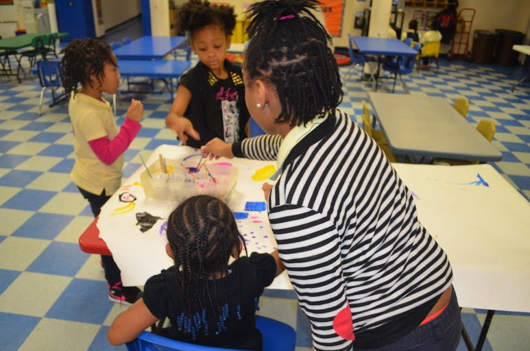 Adult and three children gathered around a table with art supplies
