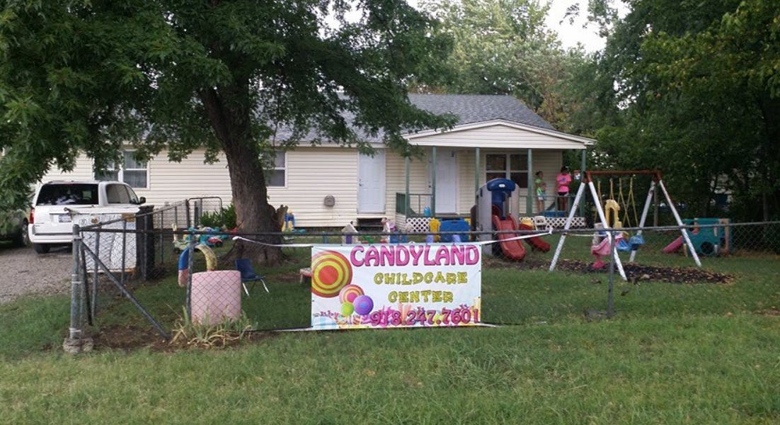 Candyland Childcare Center sign in front of a house with a swing set