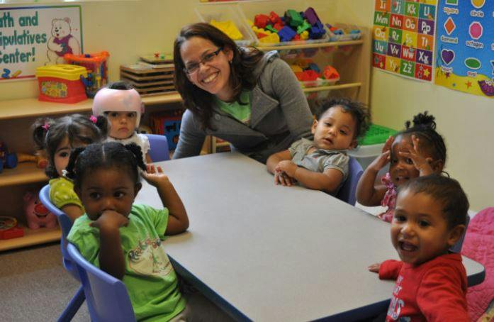 Adult and multiple children sitting around a table in a classroom