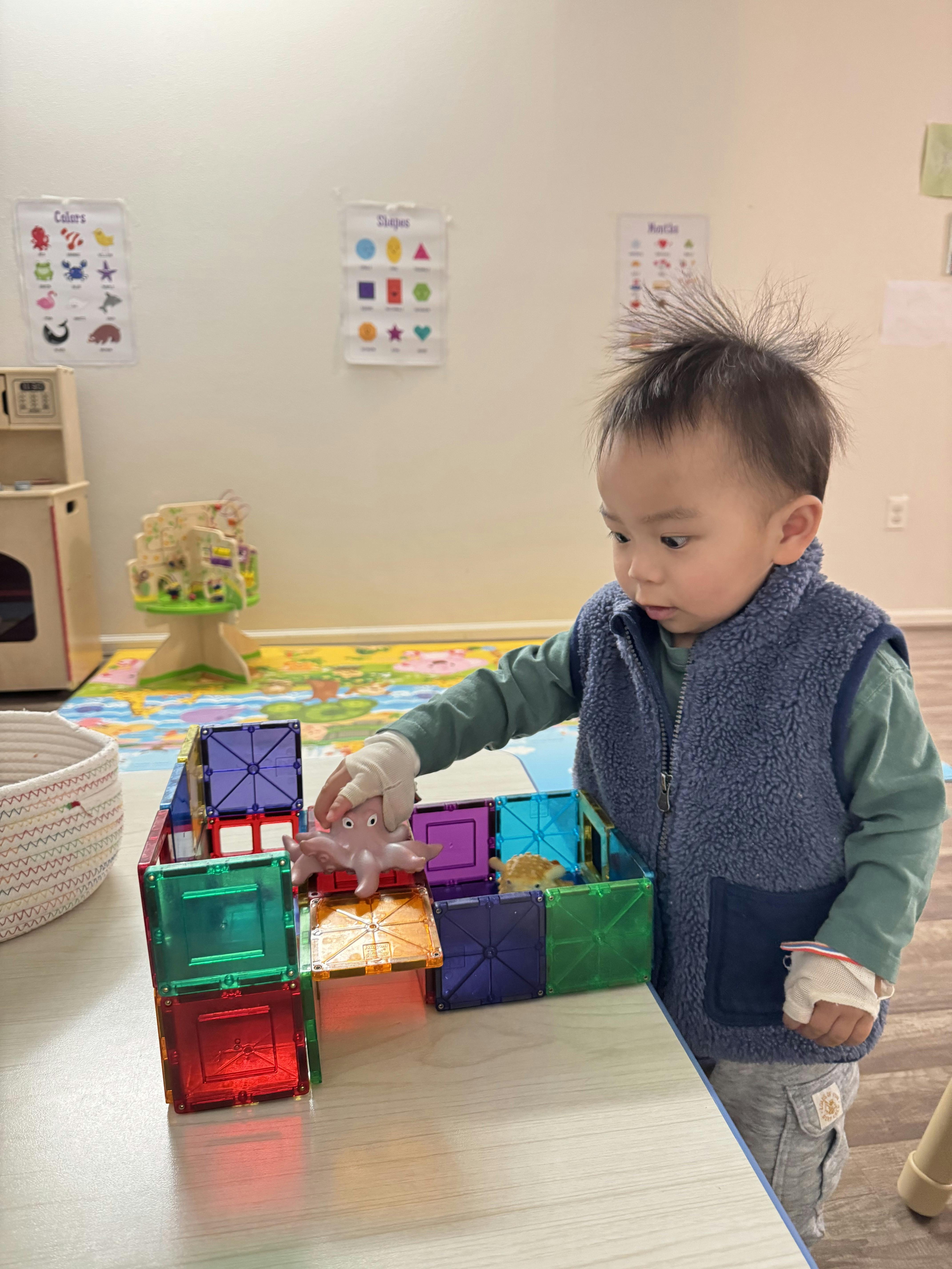 Child playing with colorful magnetic tiles and a toy octopus