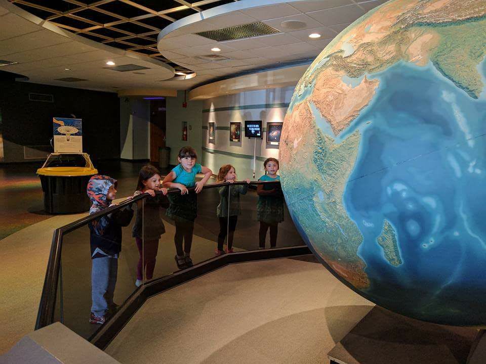 Children looking at a large globe in a museum